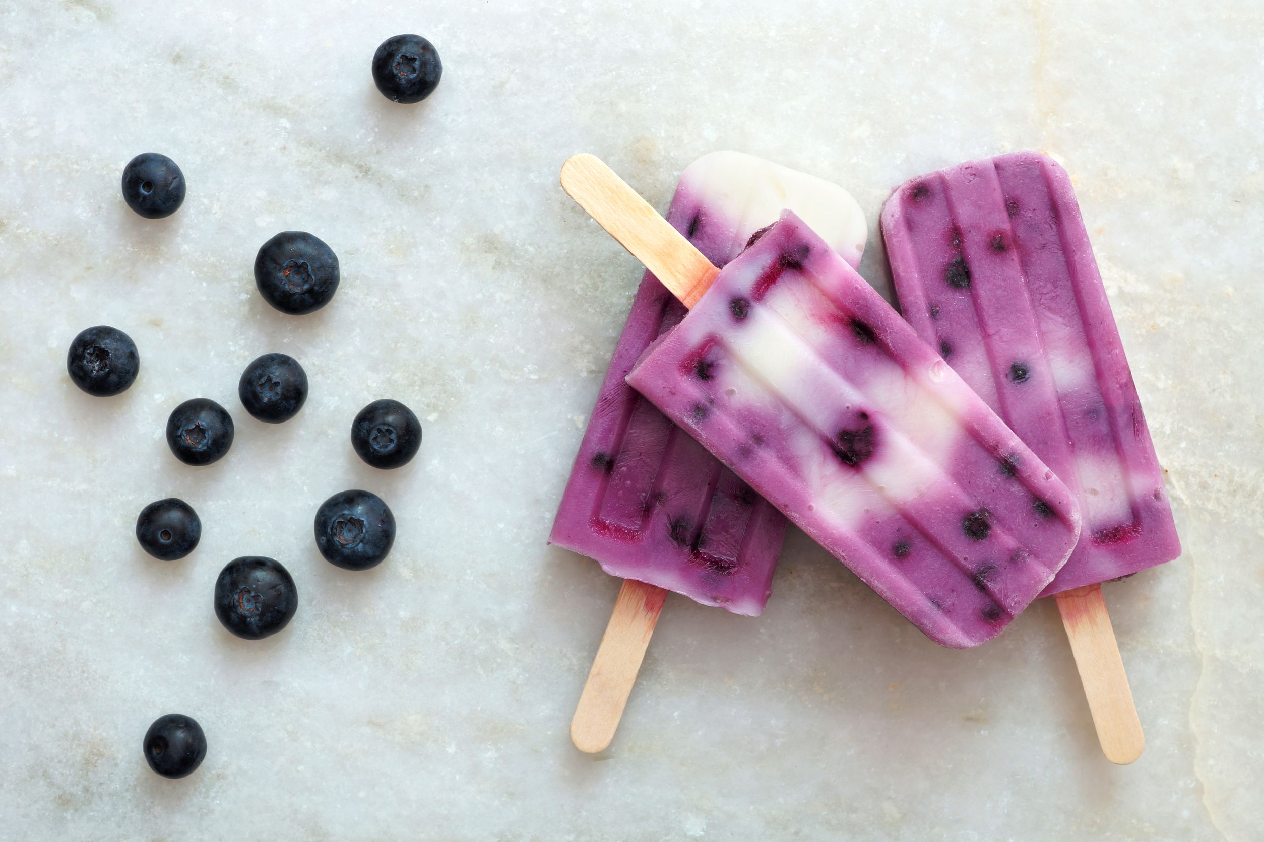 40300505 – blueberry vanilla ice pops in a cluster on a white marble background